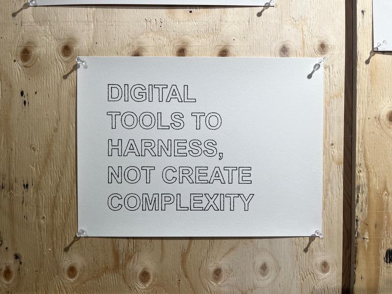 Manifesto pinned to plywood reading Digital tools to harness, not create complexity